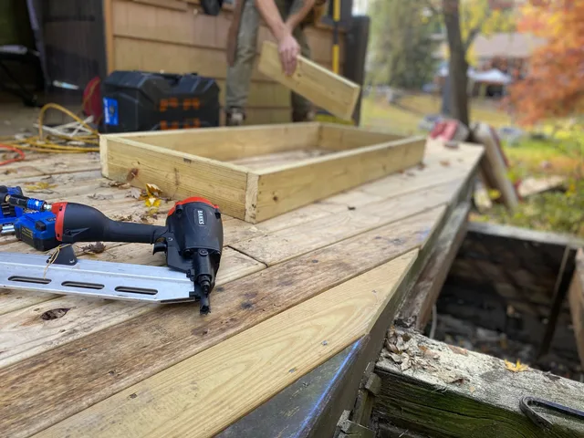 Close-up of carpentry work on a deck with a nail gun and wooden frame under construction. Sådan vælger du en lokal håndværker: tilbud, aftale og kontrol